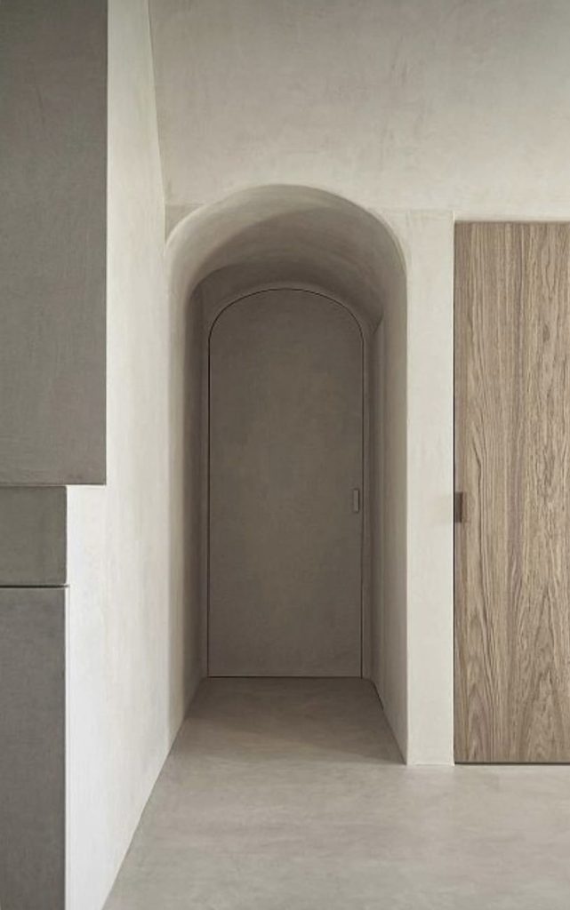 Porte cintrée avec voûte en enduit minéral dans un intérieur contemporain aux lignes épurées