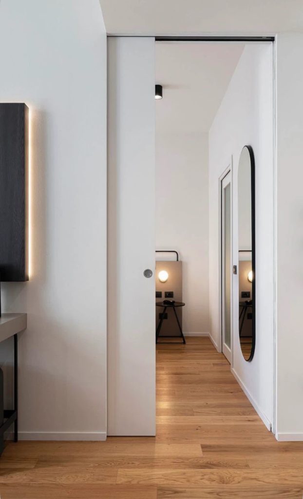 Porte à galandage en bois intégrée dans une chambre contemporaine minimaliste