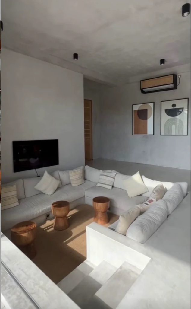 Salon moderne minimaliste avec canapé d'angle blanc, cheminée et décoration contemporaine