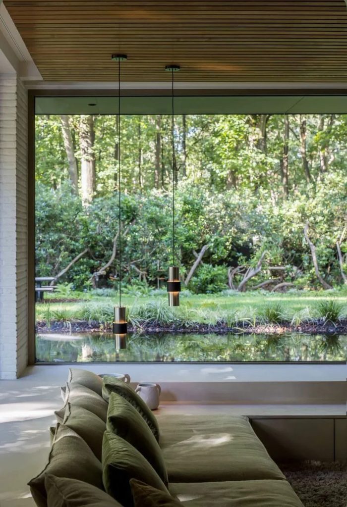 Salon en contrebas ouvert sur un jardin grâce à une baie vitrée toute hauteur