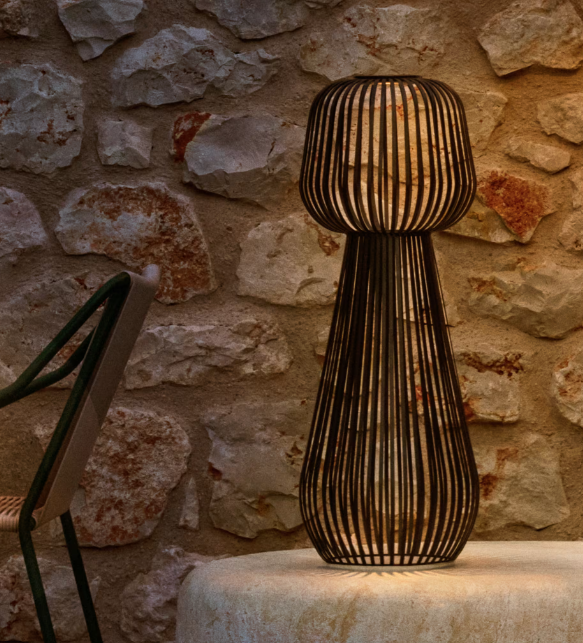 Lampe d'extérieur design en fibres tressées devant un mur en pierre naturelle