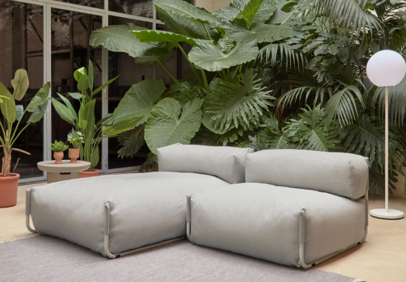 Pouf d'extérieur modulable en tissu écru sur une terrasse avec végétation tropicale